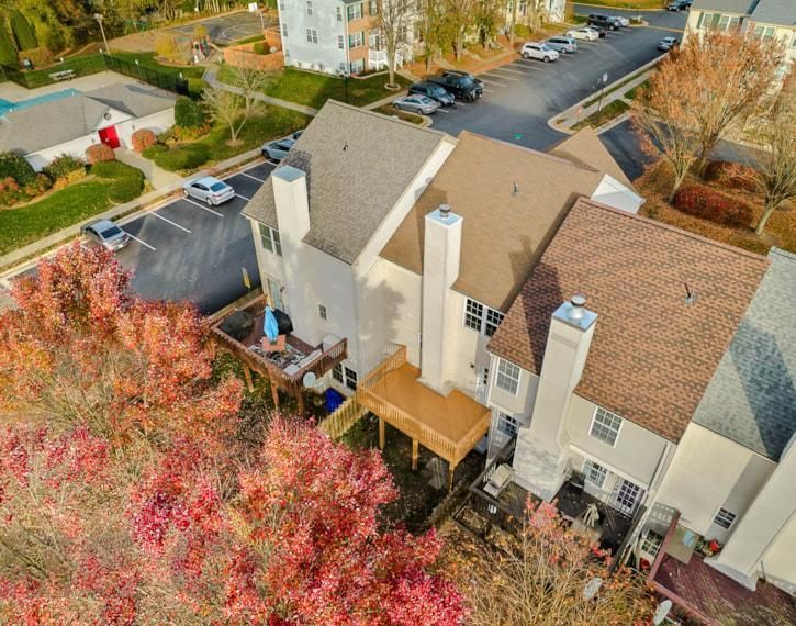 Aerial view of beige apartment buildings beside a parking lot and autumn trees.