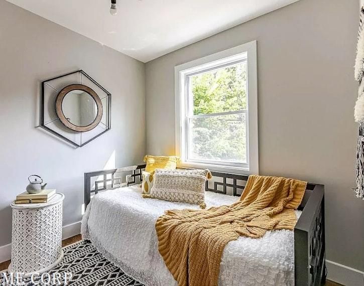 Bright gray bedroom with a white daybed, mustard throw, window, and round wall mirror