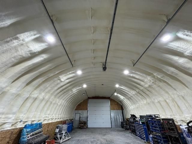 A large warehouse with a garage door and lots of tools in it