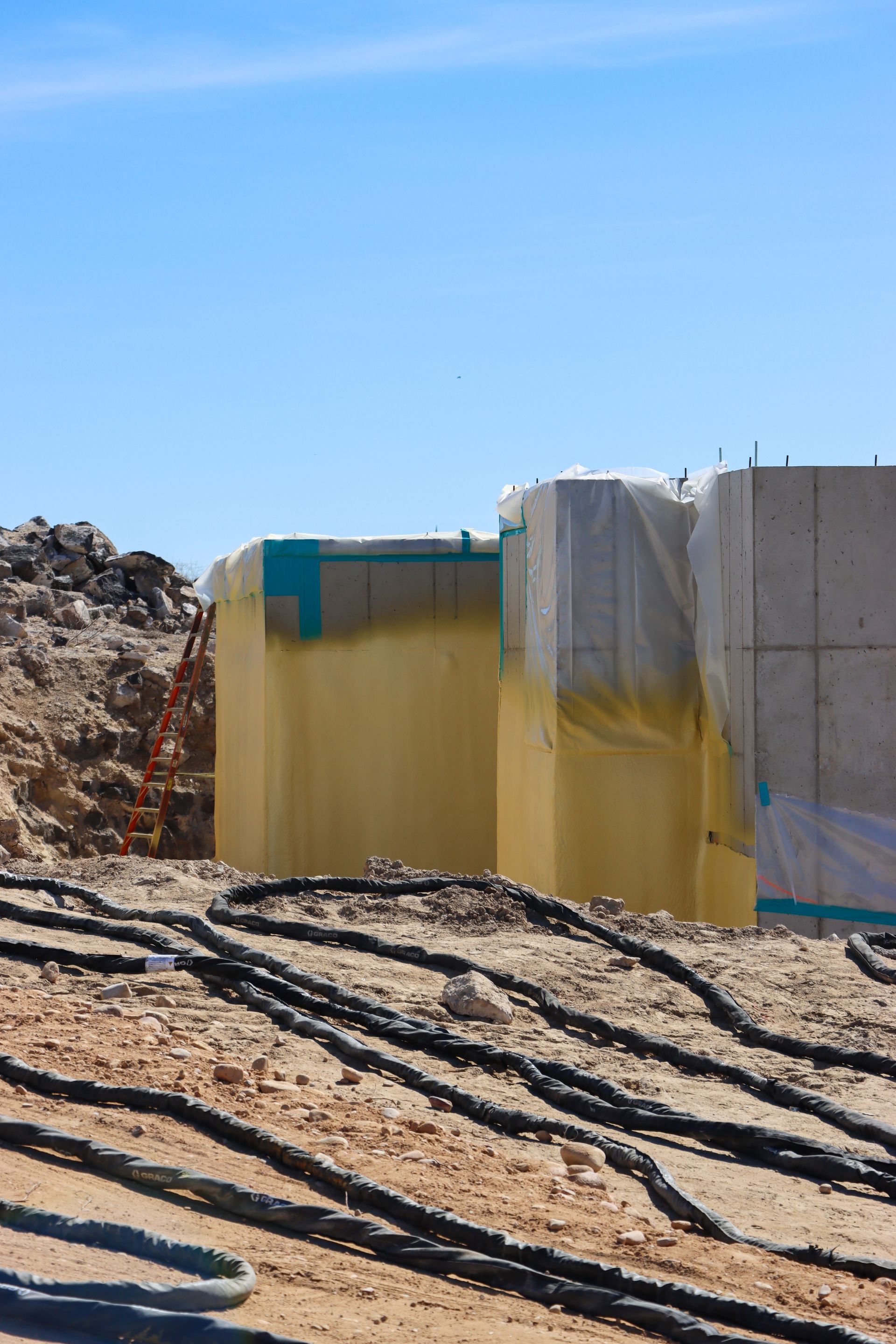 A building is being built in the desert with a lot of wires laying on the ground.
