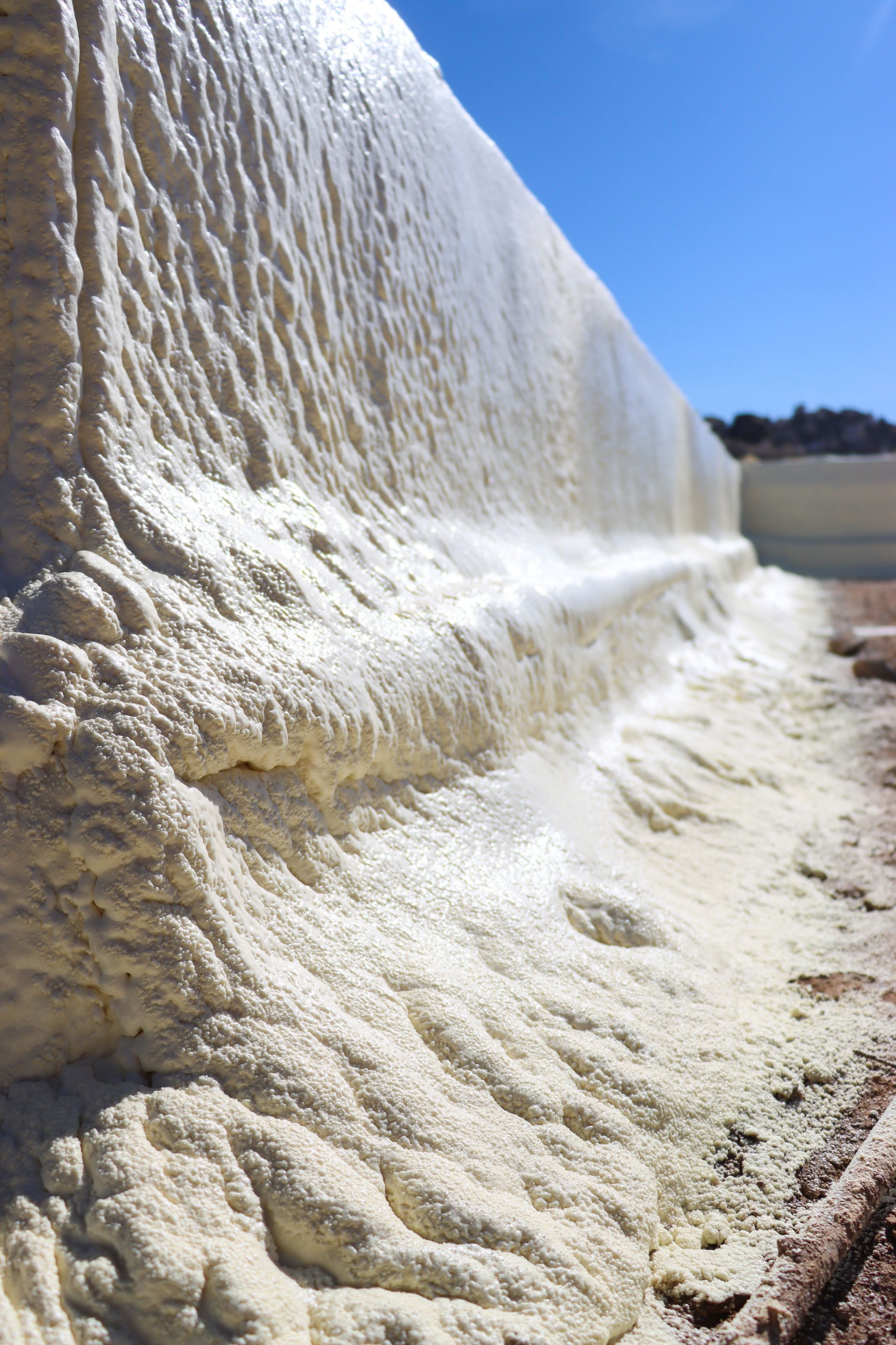 A close up of a wall covered in foam on a sunny day.