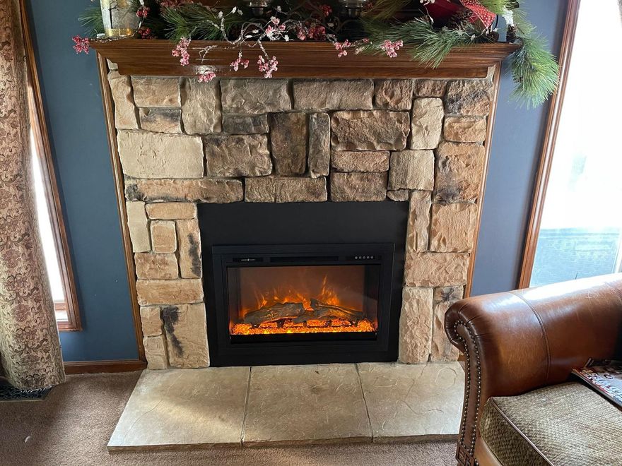 Stone fireplace with electric fire, decorated mantel.