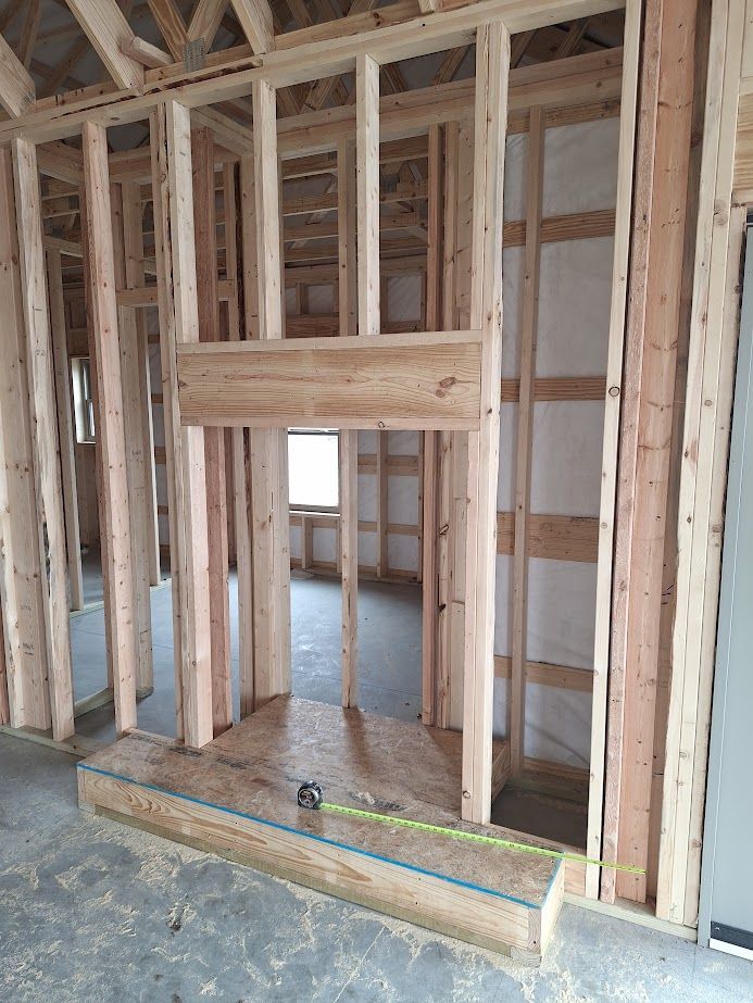 Interior house framing with a fireplace structure under construction. Wooden studs and beams.