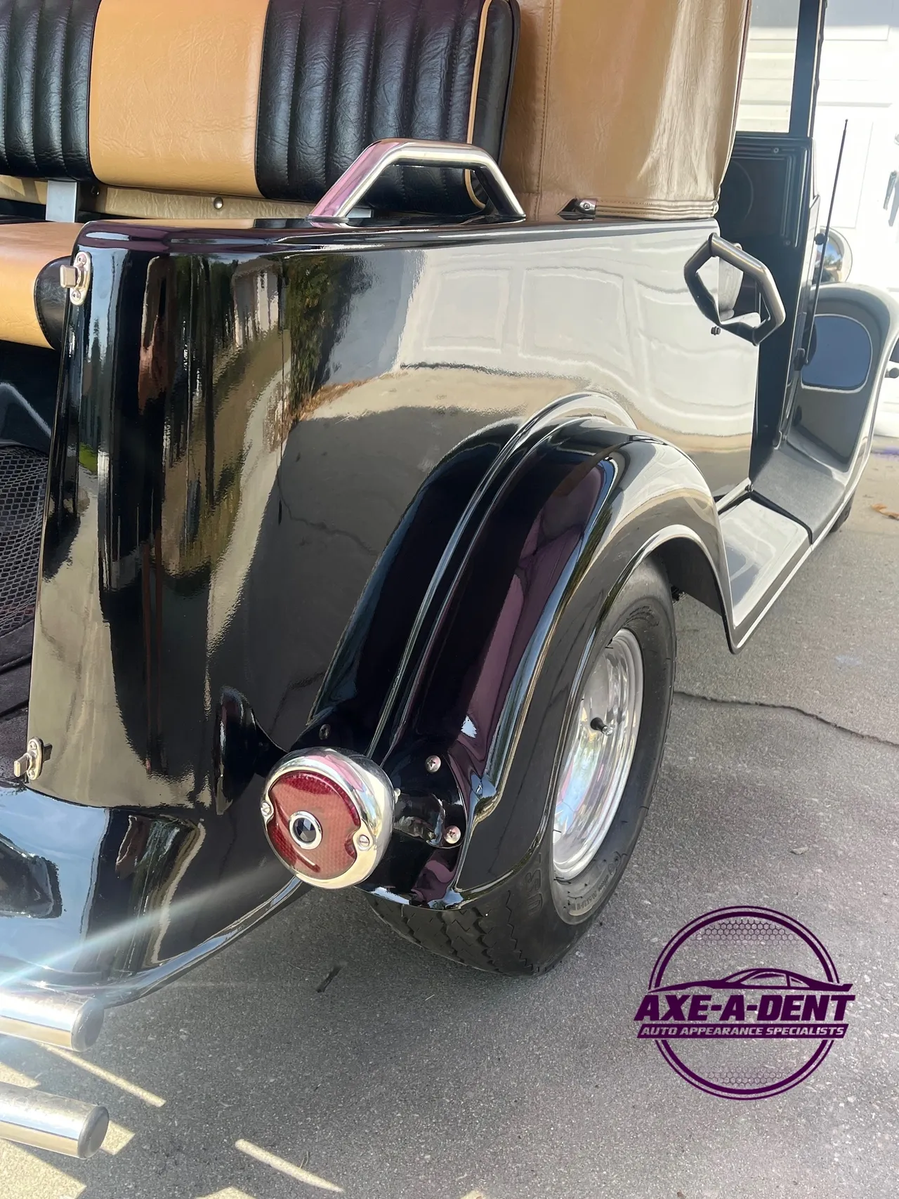 Black and tan golf cart with chrome accents, a rounded rear fender, and a circular tail light.