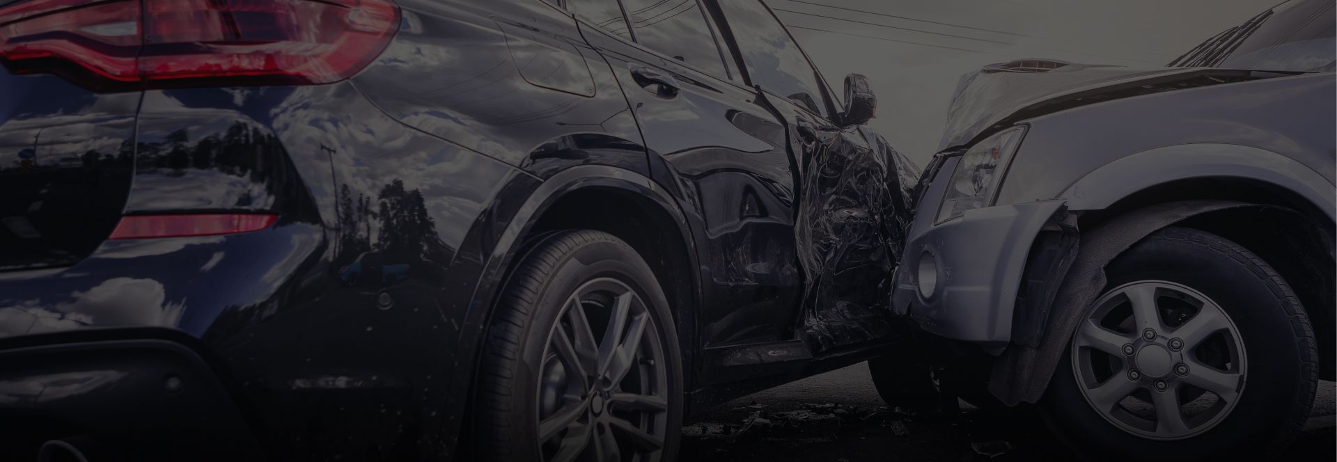 A silver SUV driving toward the viewer on a dark street, warehouses on both sides | Axe-A-Dent Auto Collision