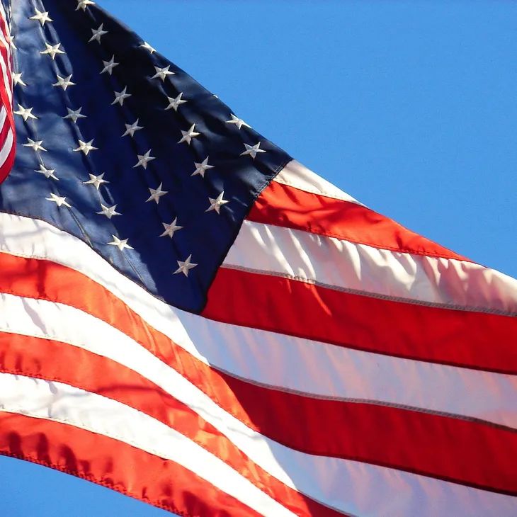 American flag waving against a bright blue sky.