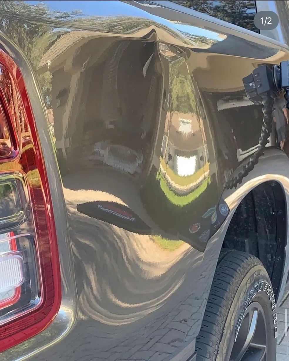 Damaged gray car rear panel with a large dent.