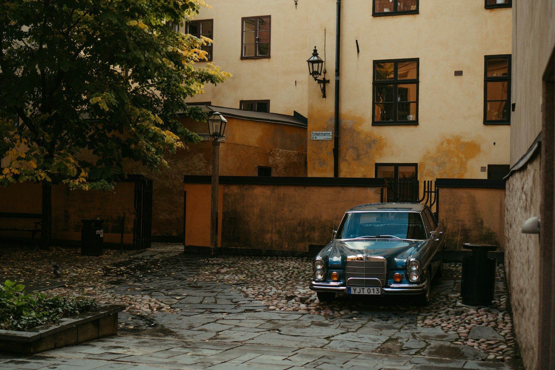 Blue vintage car parked in a cobblestone courtyard in Gamla Stan