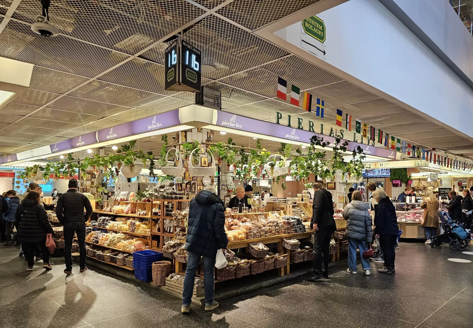 Hötorgshallen with hanging plants and produce, shoppers browsing under a patterned ceiling