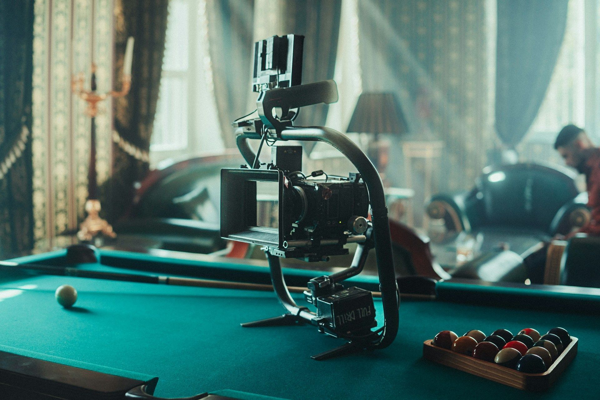 Pool table with a mechanical arm-like device over the felt, in a dimly lit room.