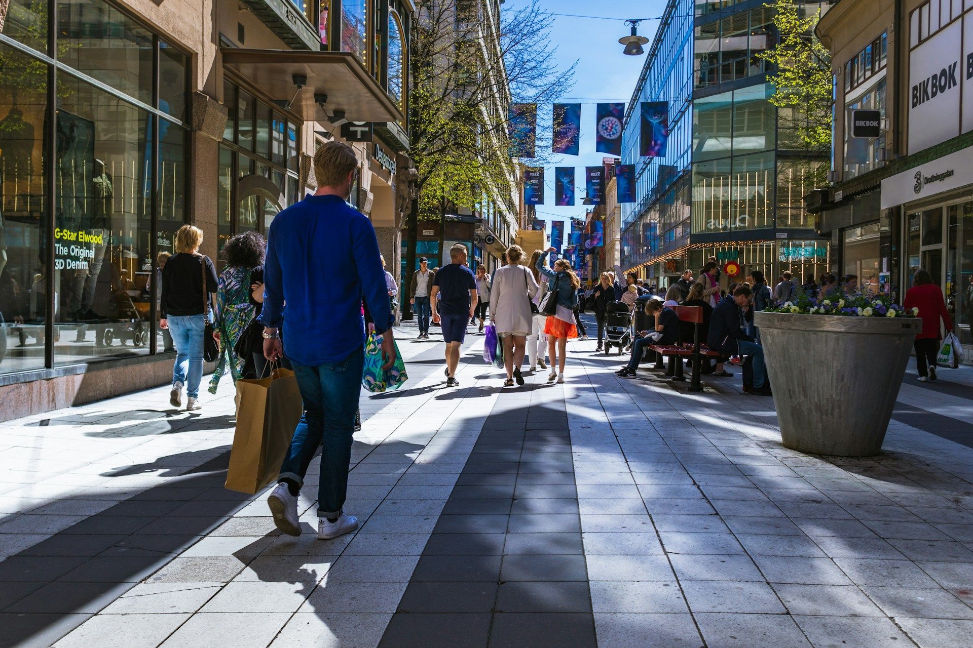 Drottninggatan with people walking between modern buildings in bright sunlight
