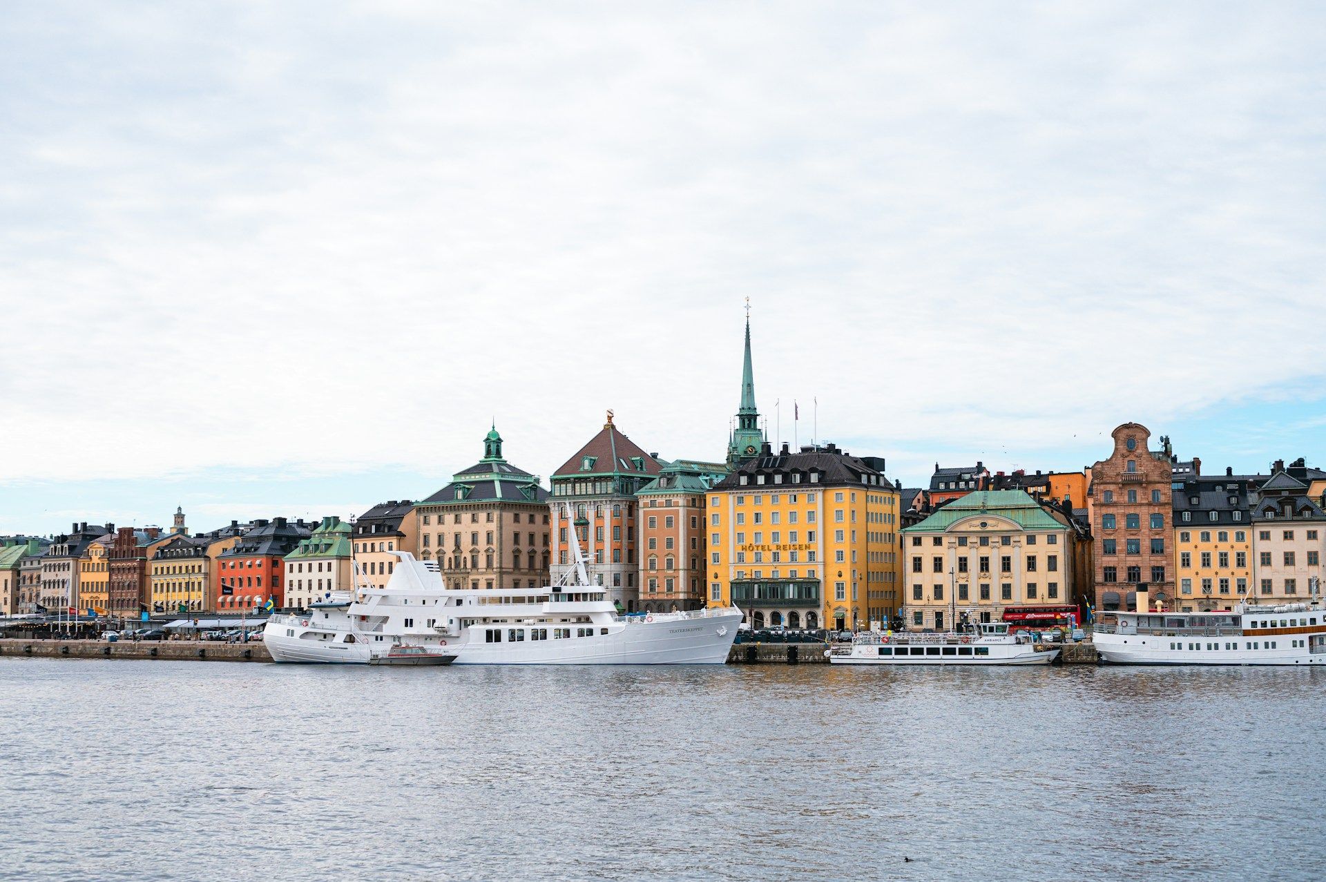 Colorful waterfront buildings in Stockholm with boats along a calm harbor under a cloudy sky
