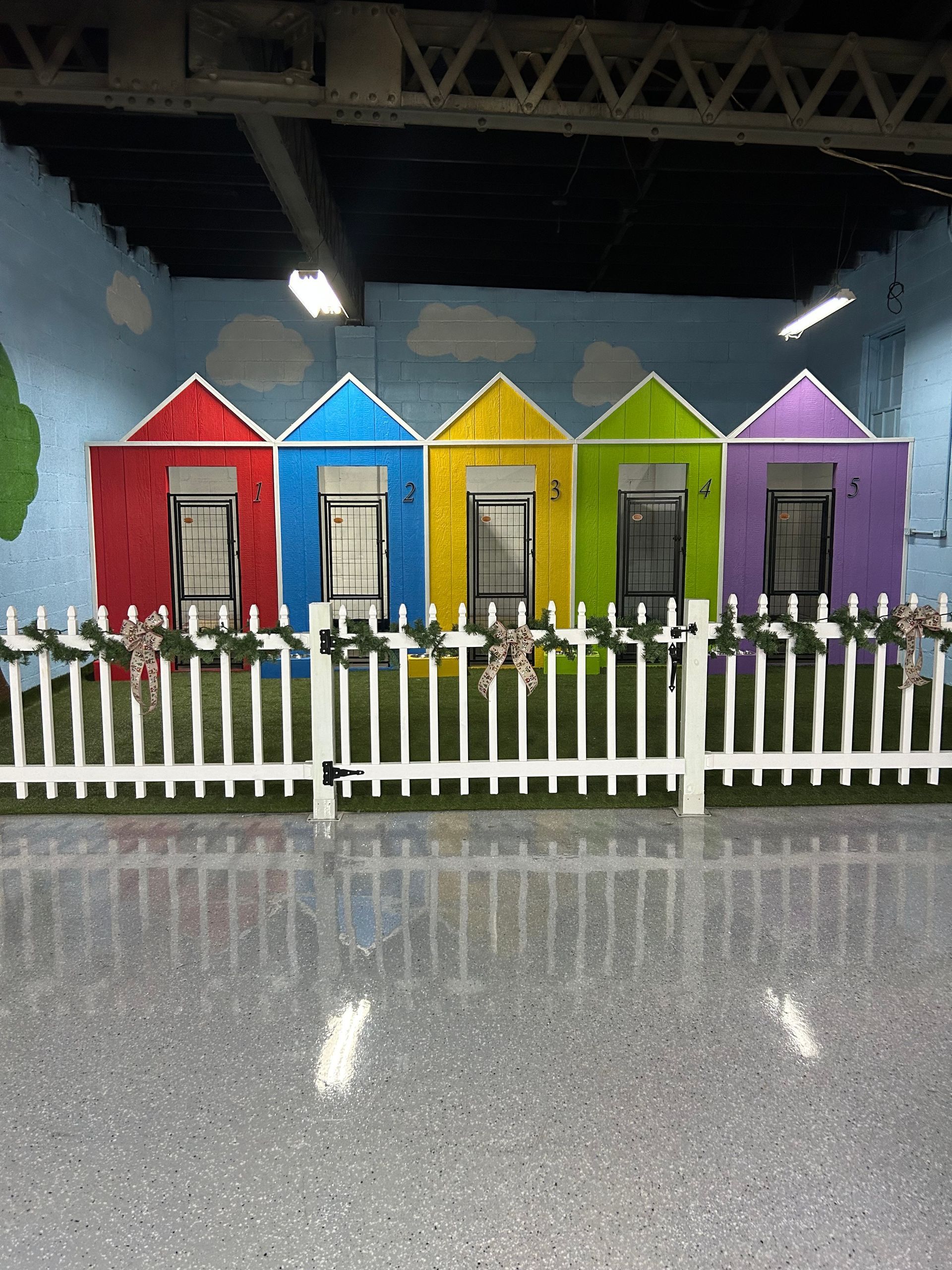 Colorful houses behind a white picket fence on a reflective floor.