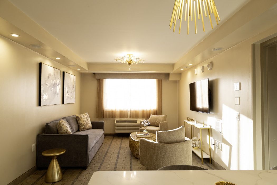 Modern living room with beige sofas, wall-mounted TV, and bright window light