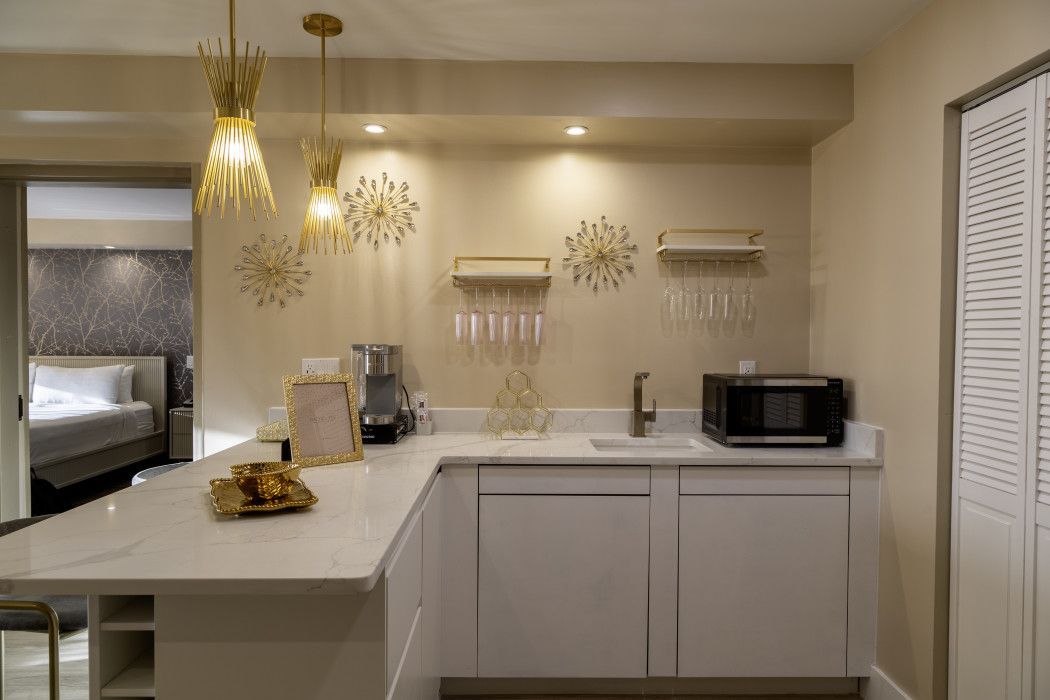 Modern kitchen with white cabinets, island, pendant lights, and a microwave on the counter.