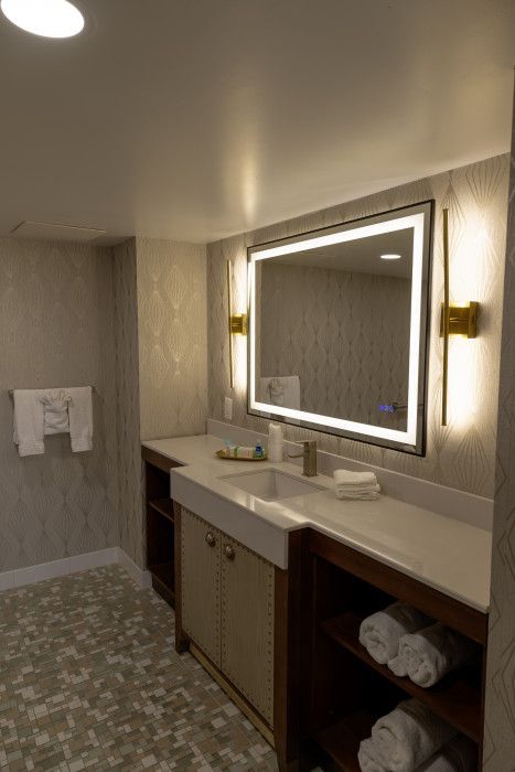 Modern bathroom with large mirror, double vanity, beige walls, and towel rack