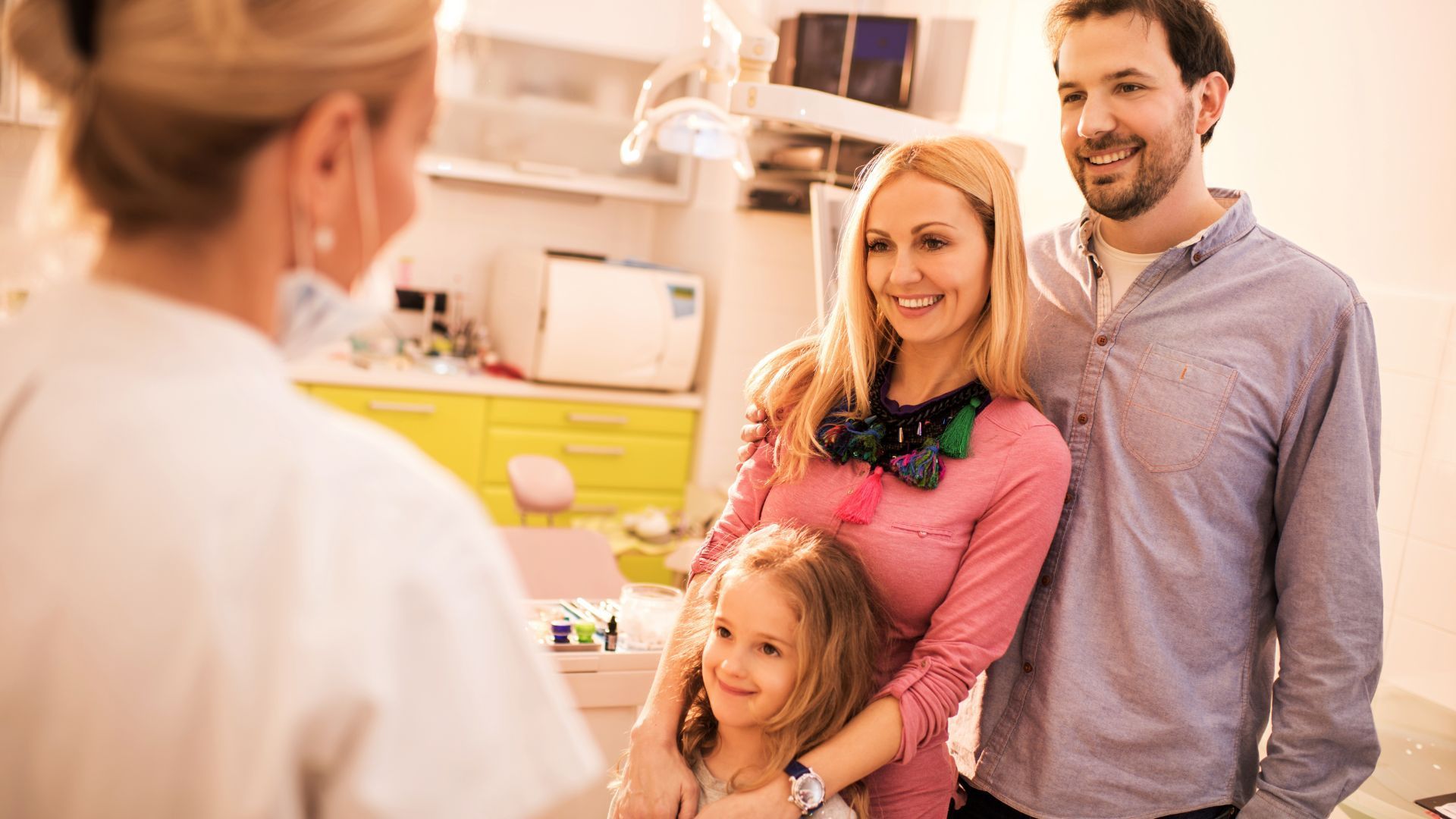 A family is standing in front of a dentist in a dental office.
