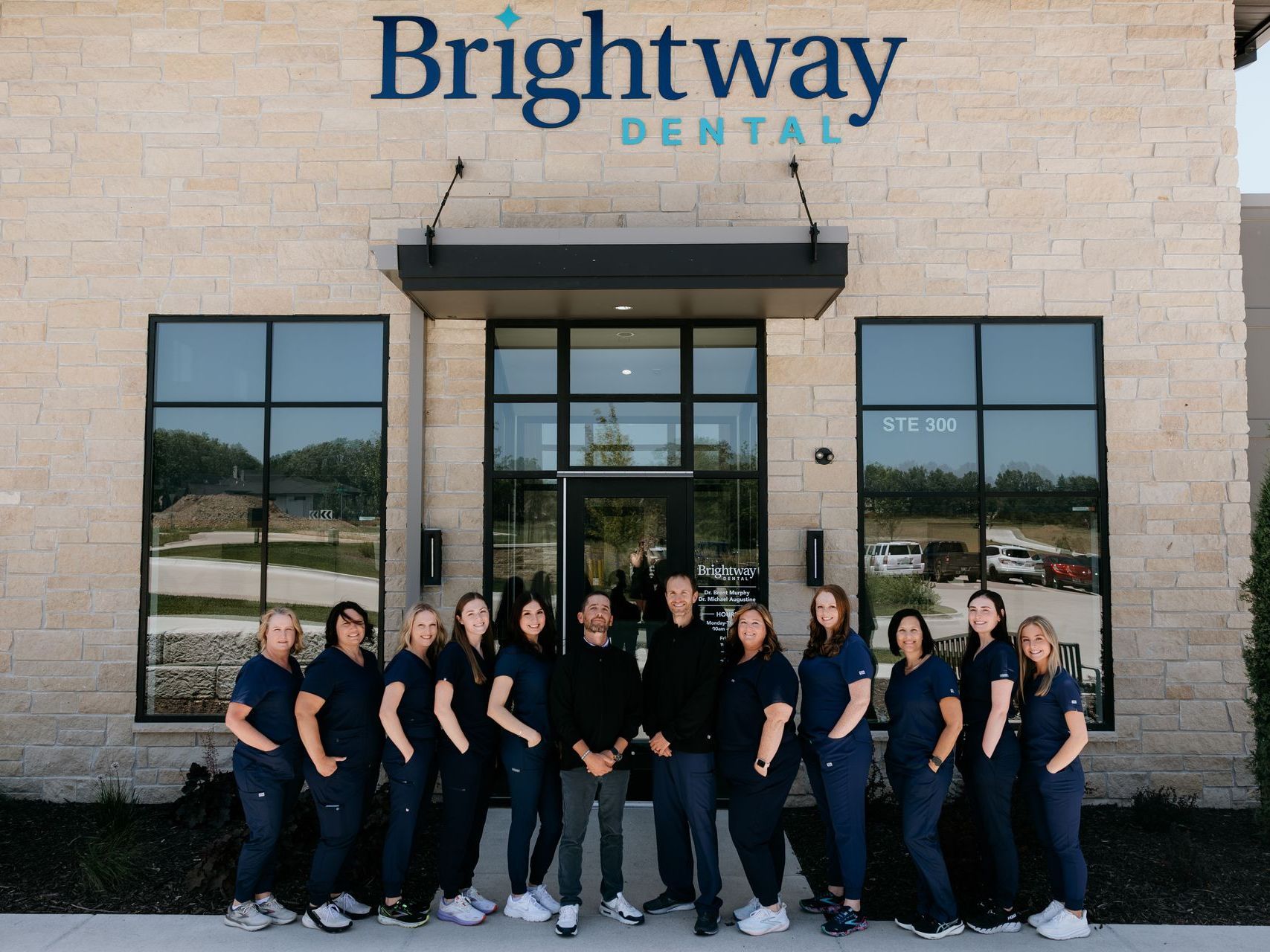 Brightway Dental staff posing outside the clinic entrance in matching black uniforms