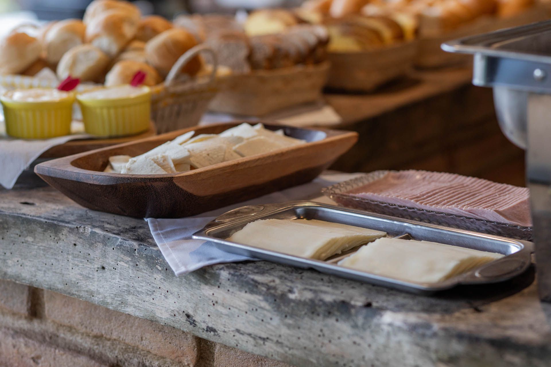 Variedade de doces e bolos em bandejas num balcão de buffet.