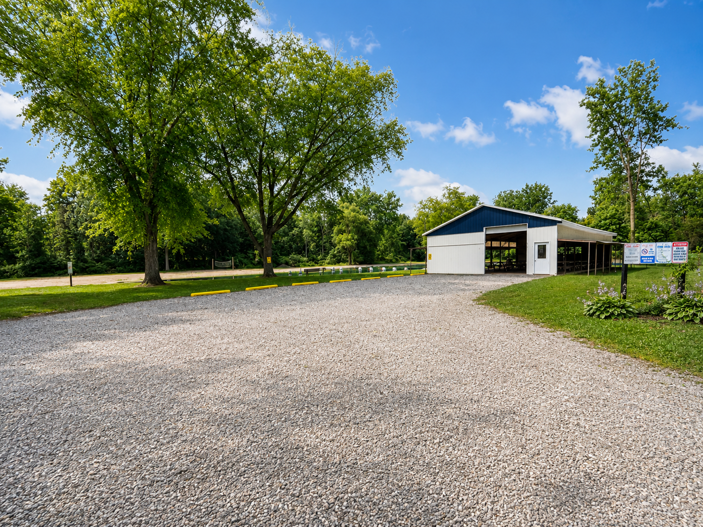 A wide view of the large parking lot for the large pavilion surounded by lush green trees