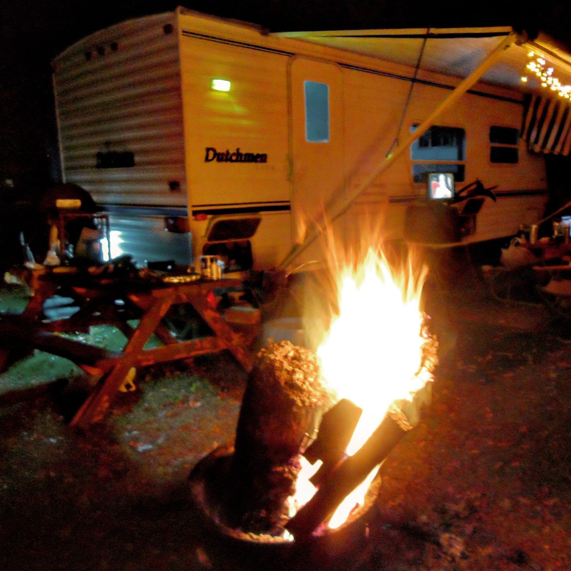 A dutchman trailer is parked next to a fire pit