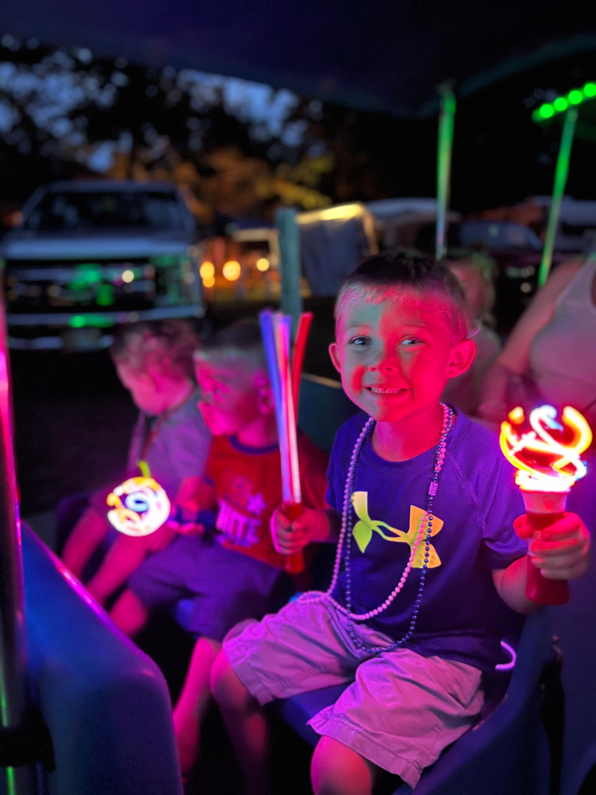 A boy wearing a blue under armour shirt is holding a light stick.