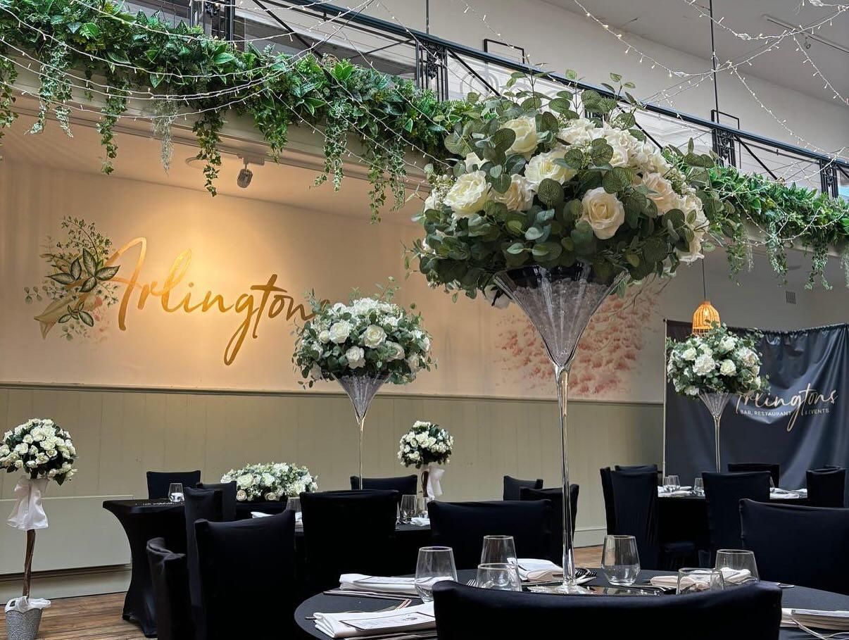 Wedding reception venue, round tables with white linens and burlap accents, soft lighting.