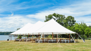 A large white tent is sitting in the middle of a grassy field.
