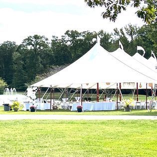 A large white tent is sitting in the middle of a grassy field.