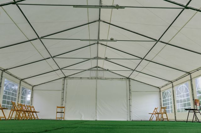A large white tent with chairs and tables inside of it.