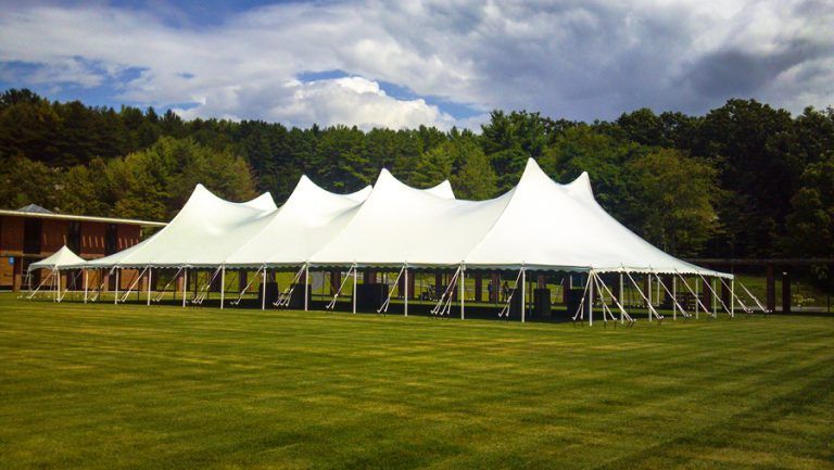 A large white tent is sitting in the middle of a grassy field.