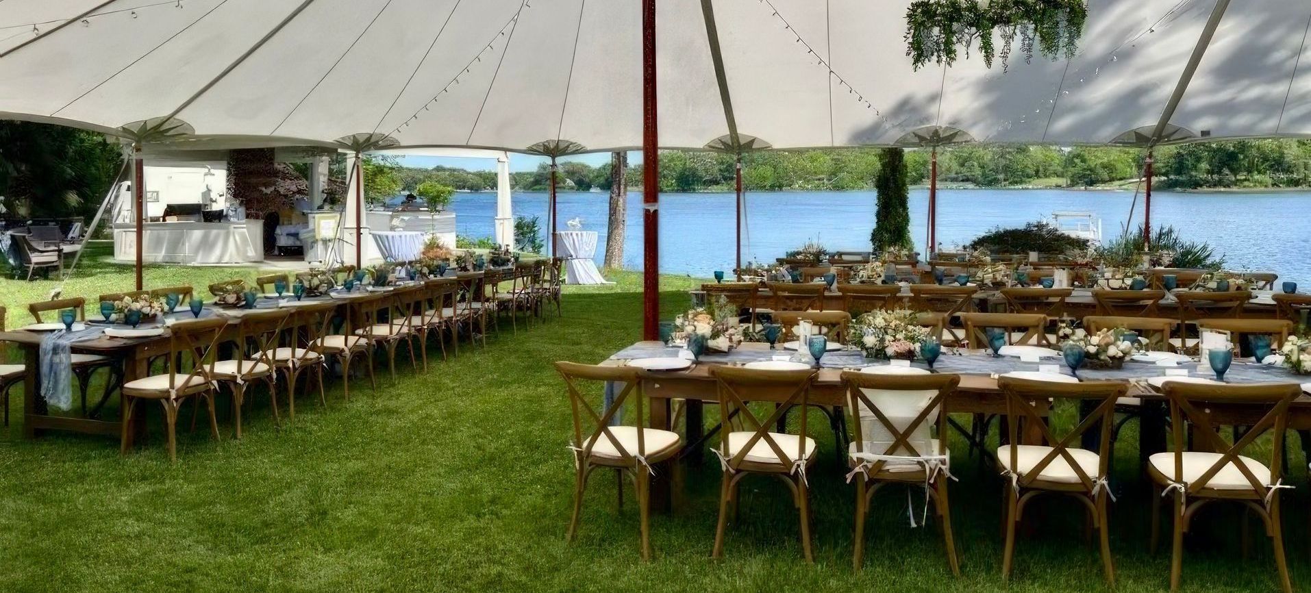 A large tent with tables and chairs set up for a wedding reception.