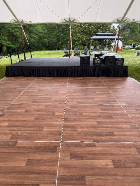 A wooden dance floor under a tent with a stage in the background.