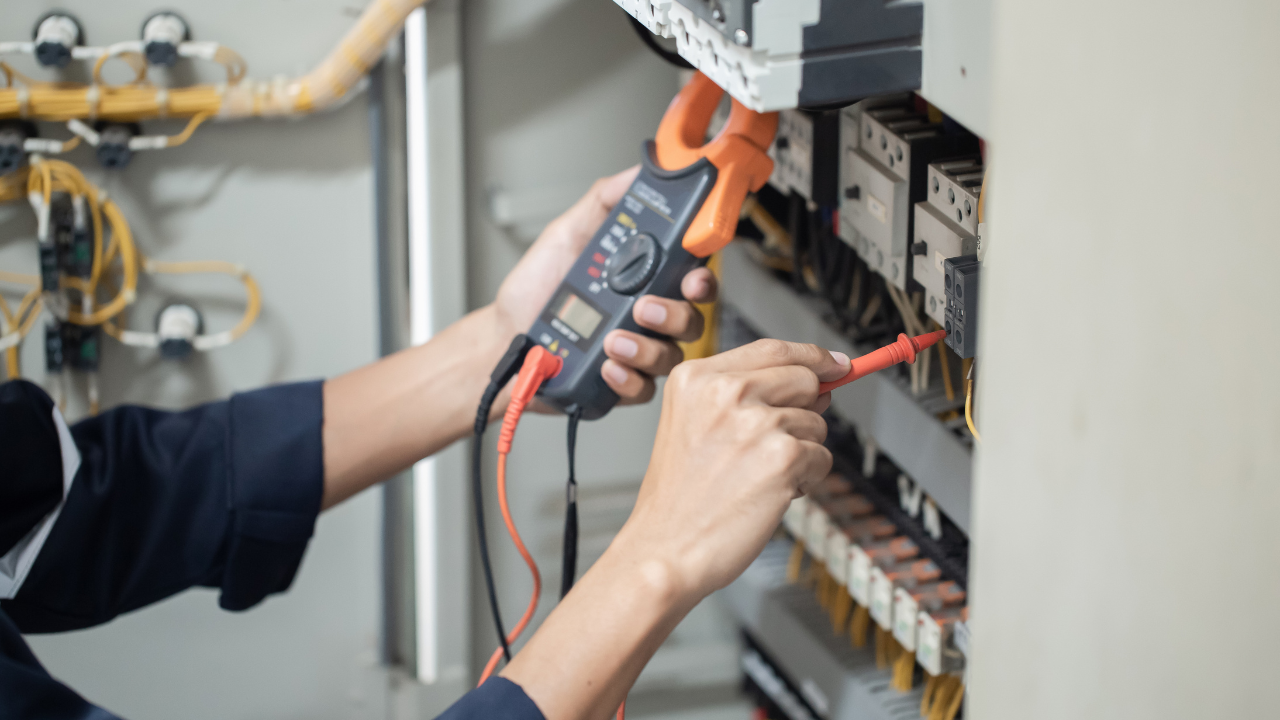 Electrician uses a multimeter to inspect electrical wiring in a panel.