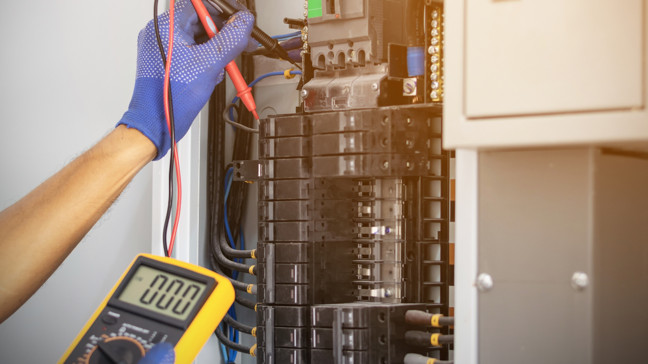 Electrician testing a circuit panel with a multimeter and gloved hand in a utility room