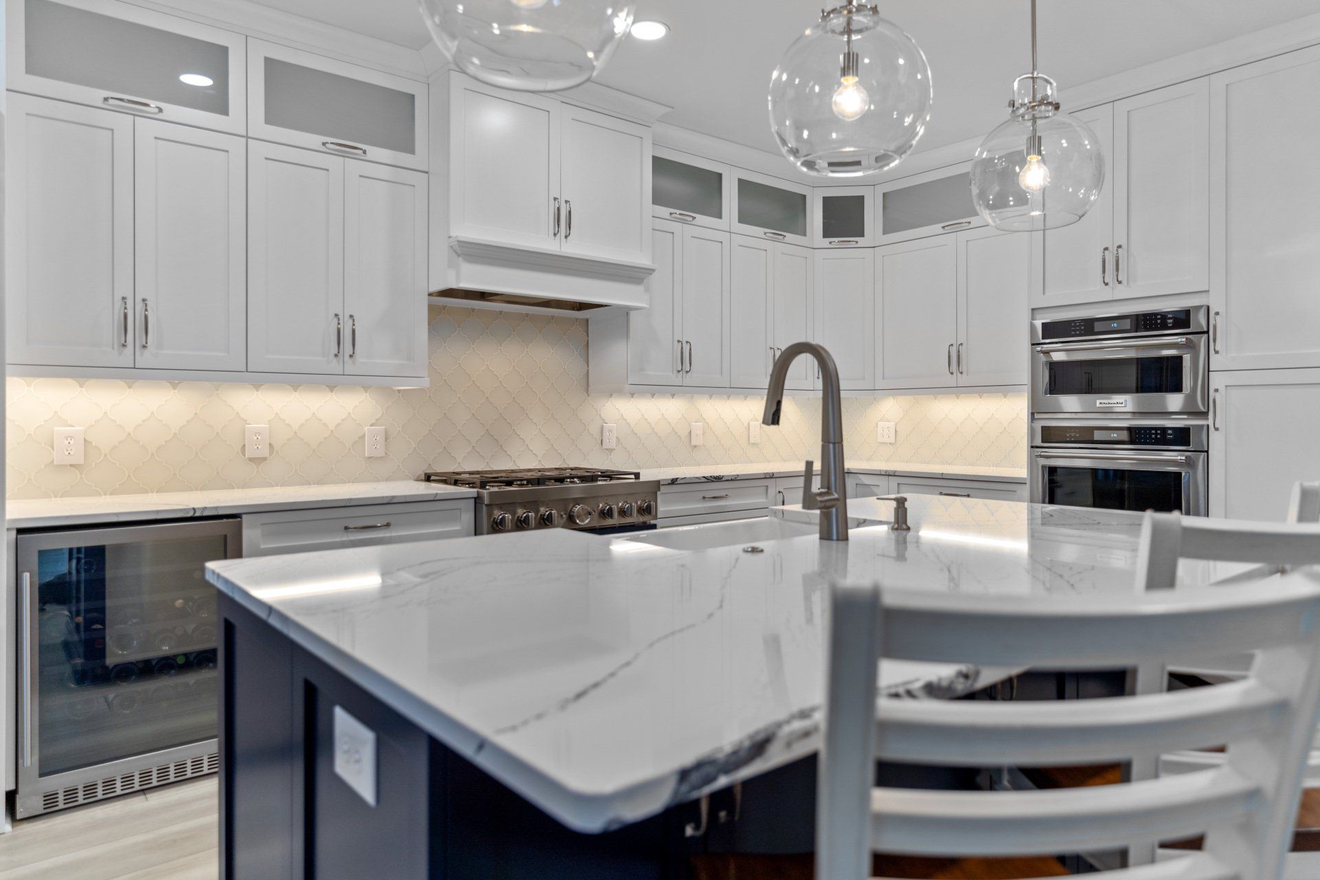 Navy blue and white kitchen with quartz countertop and pendant lights over large island.