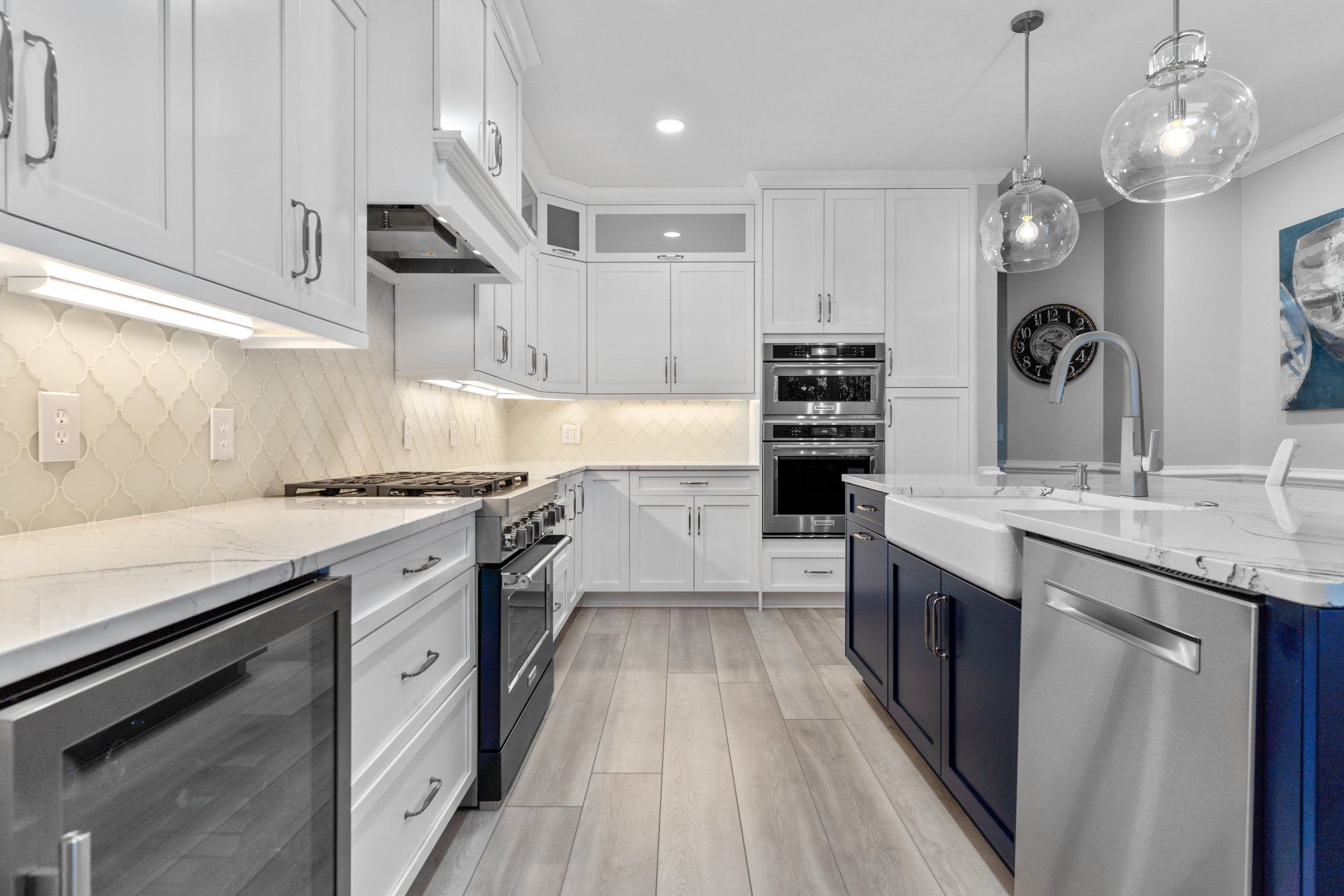 White shaker kitchen with tile backsplash and large island with farmhouse sink.