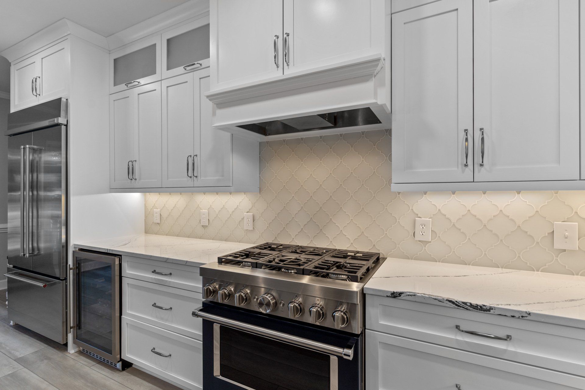 Cream arabesque glass tile kitchen backsplash with custom white shaker cabinets and Blum hardware.