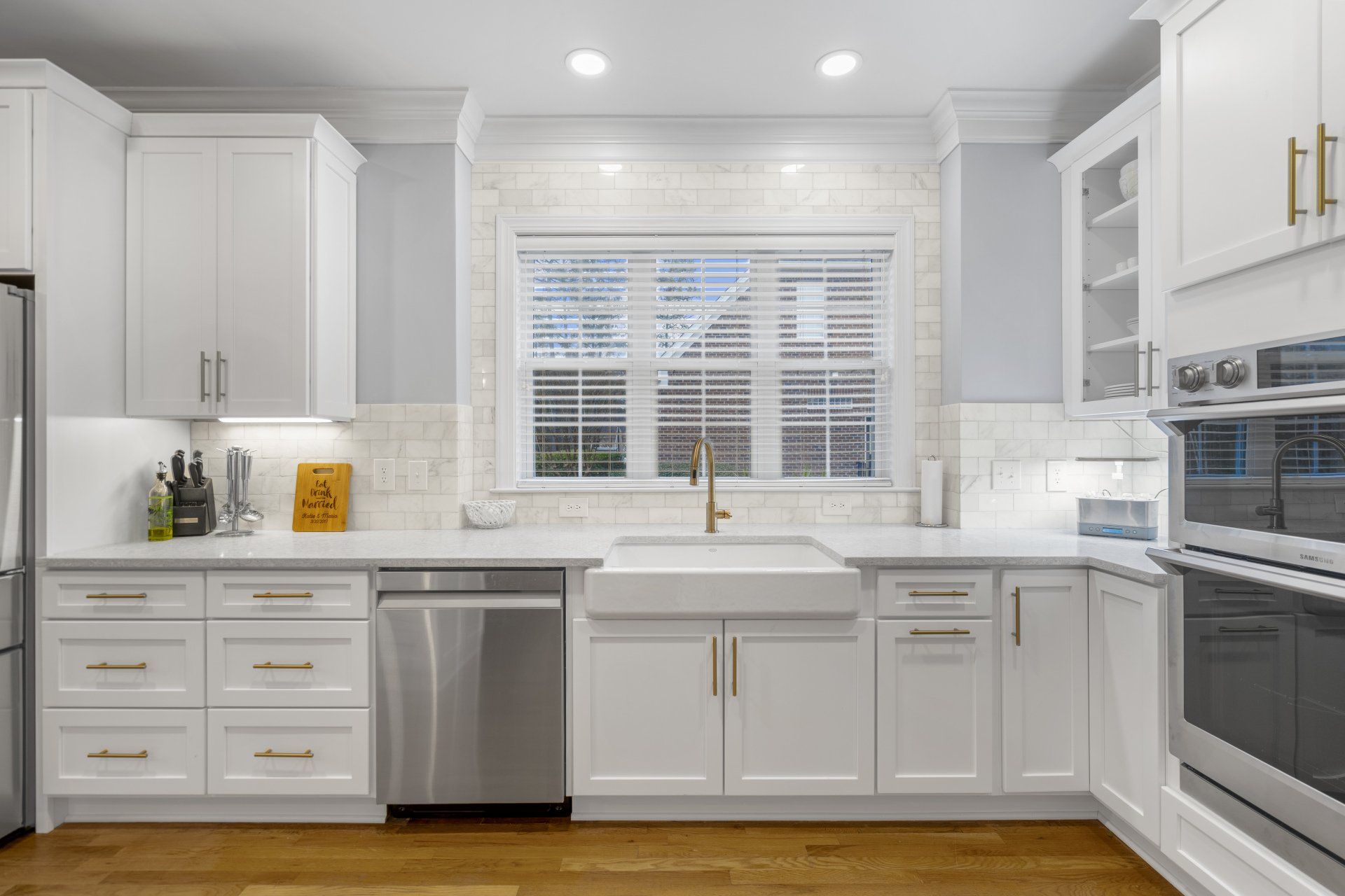 Farmhouse style apron front kitchen sink with white shaker cabinets and gold pull hardware.