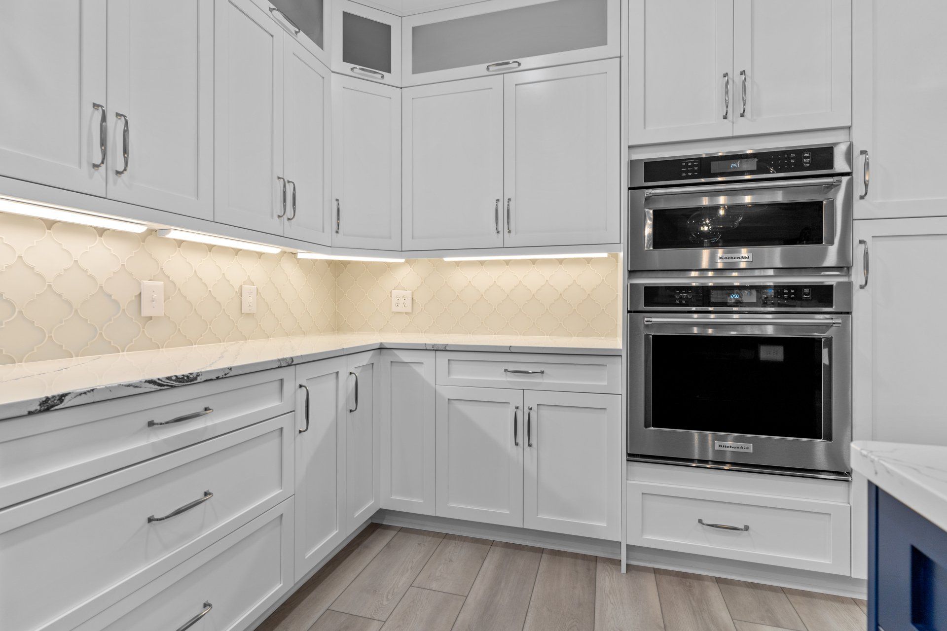 White shaker cabinets kitchen cabinets with double wall oven and arabesque glass backsplash tile.
