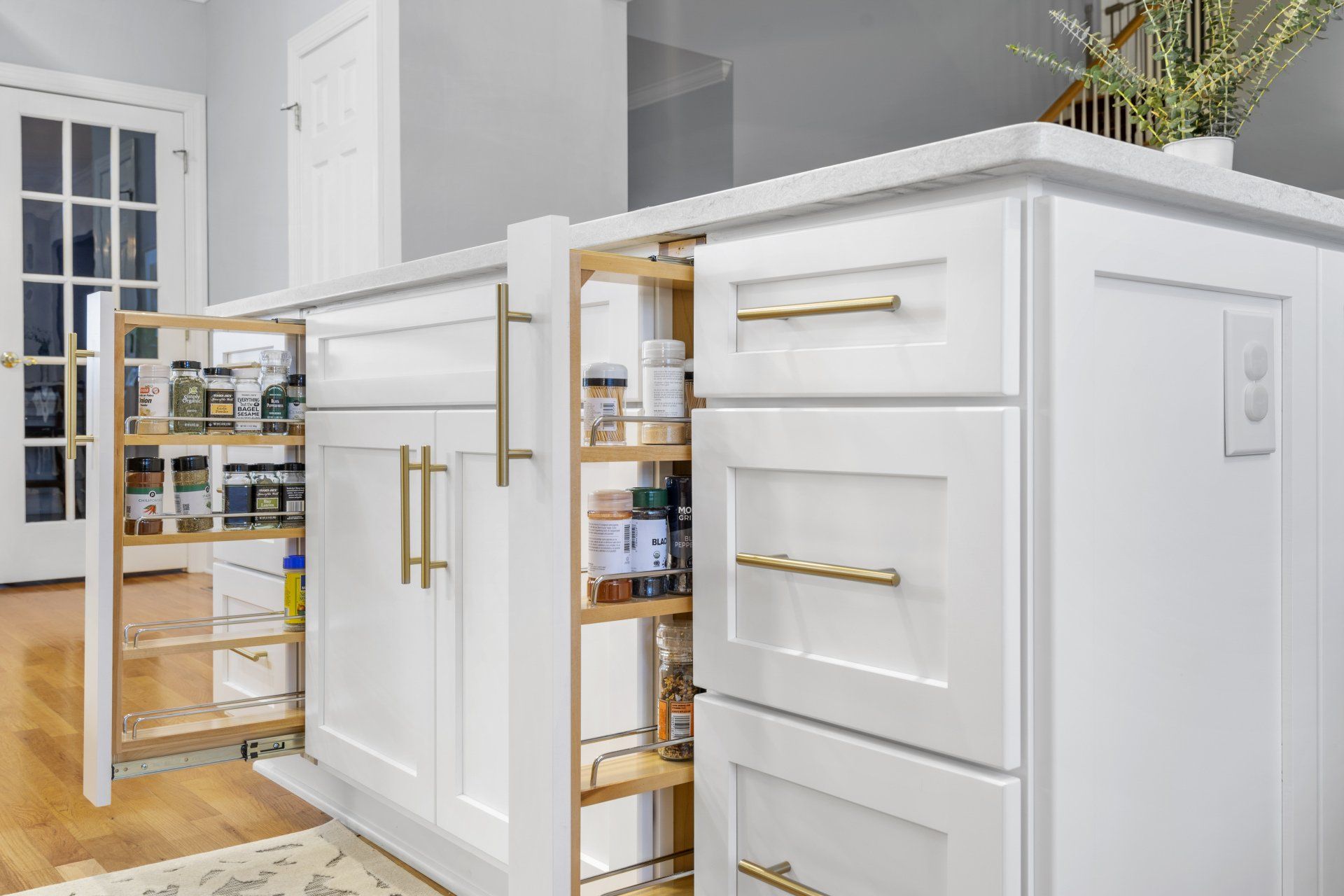 Custom white and gold cabinetry featuring pull-out spice rack cabinets
