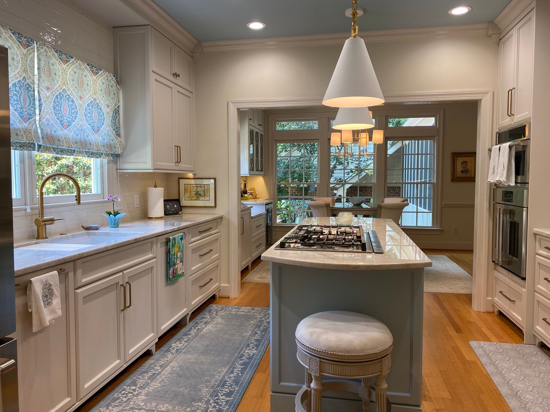 Blue kitchen island with pendant lights and gas cooktop.