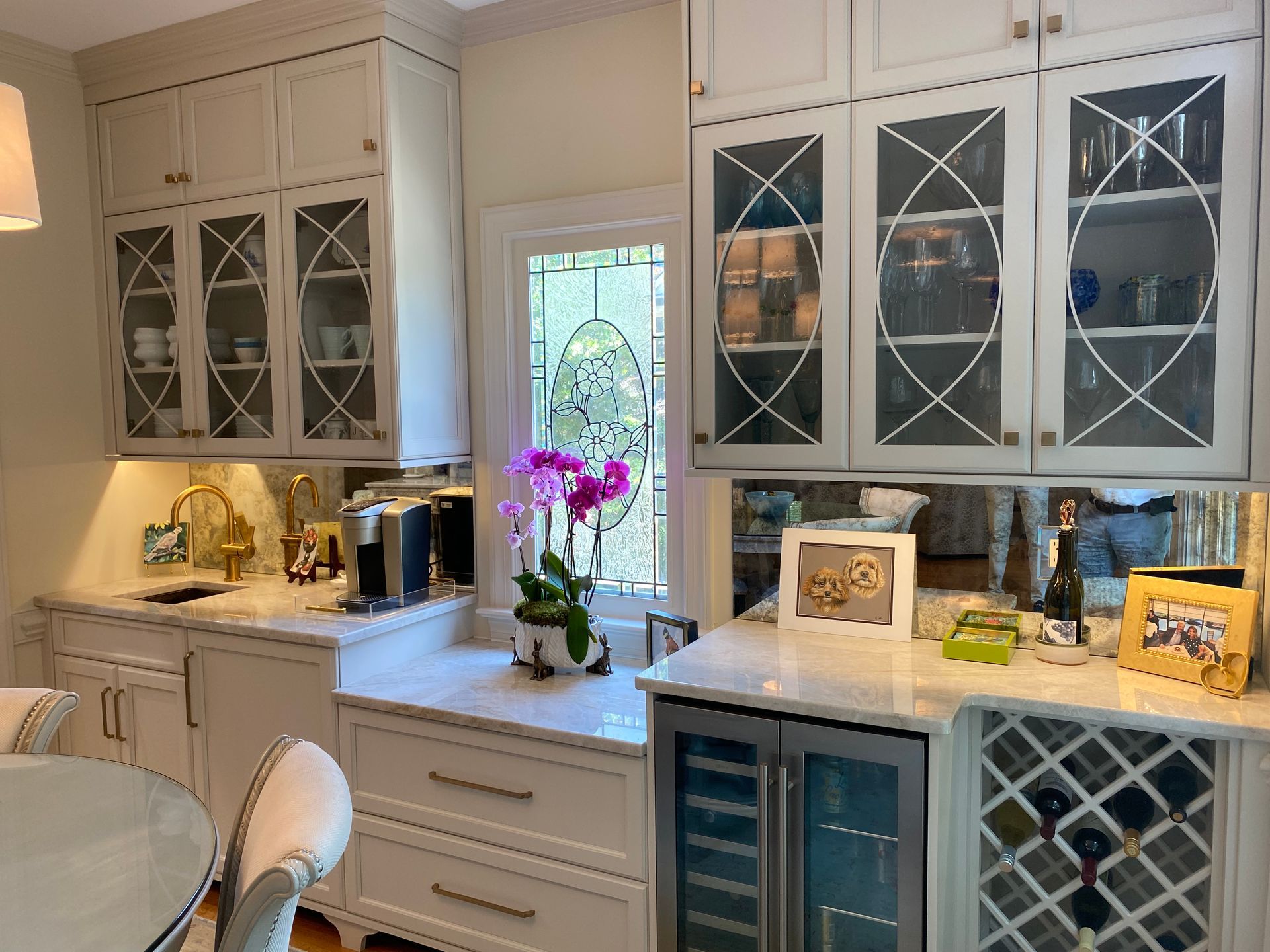 Beverage area in dining room with wine cooler and coffee bar with white shaker cabinets and glass front accent cabinets.