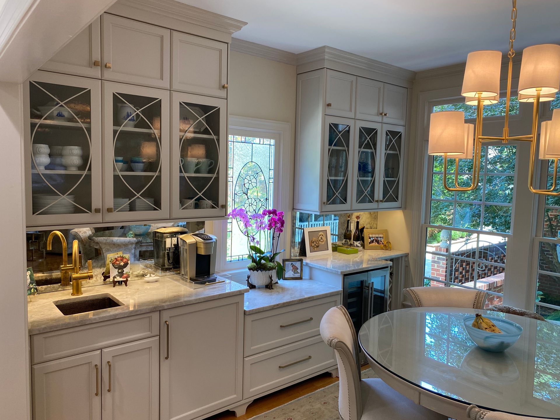Close up of wine and coffee bar area in dining room with white shaker cabinets and glass front decorative uppers/