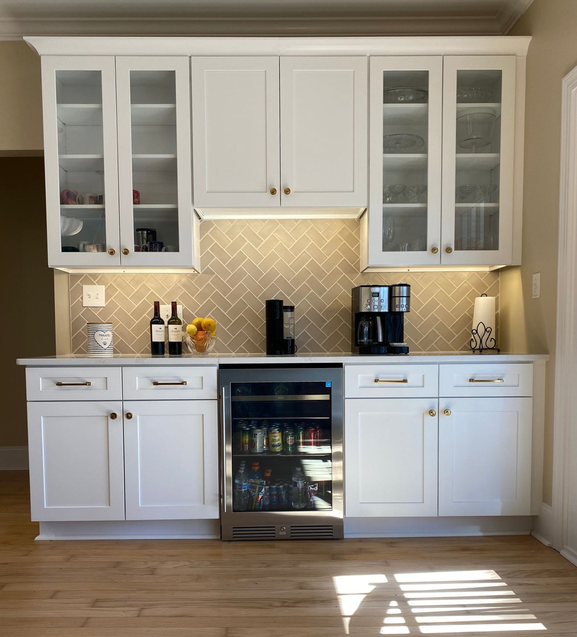 Kitchen beverage station with wine cooler and gray herringbone tile backsplash.