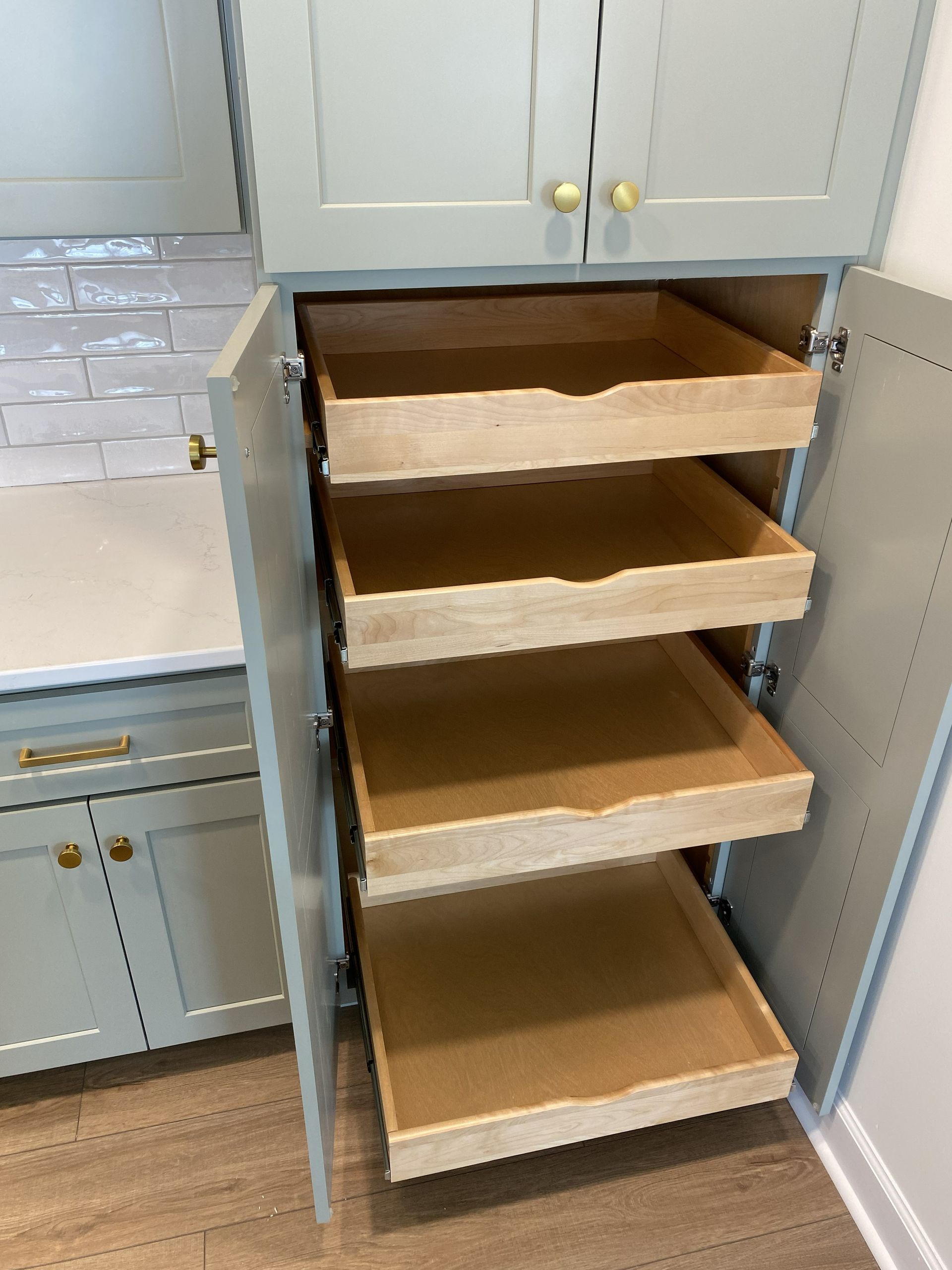Sage green pantry cabinet with pull-out drawers for easy storage.