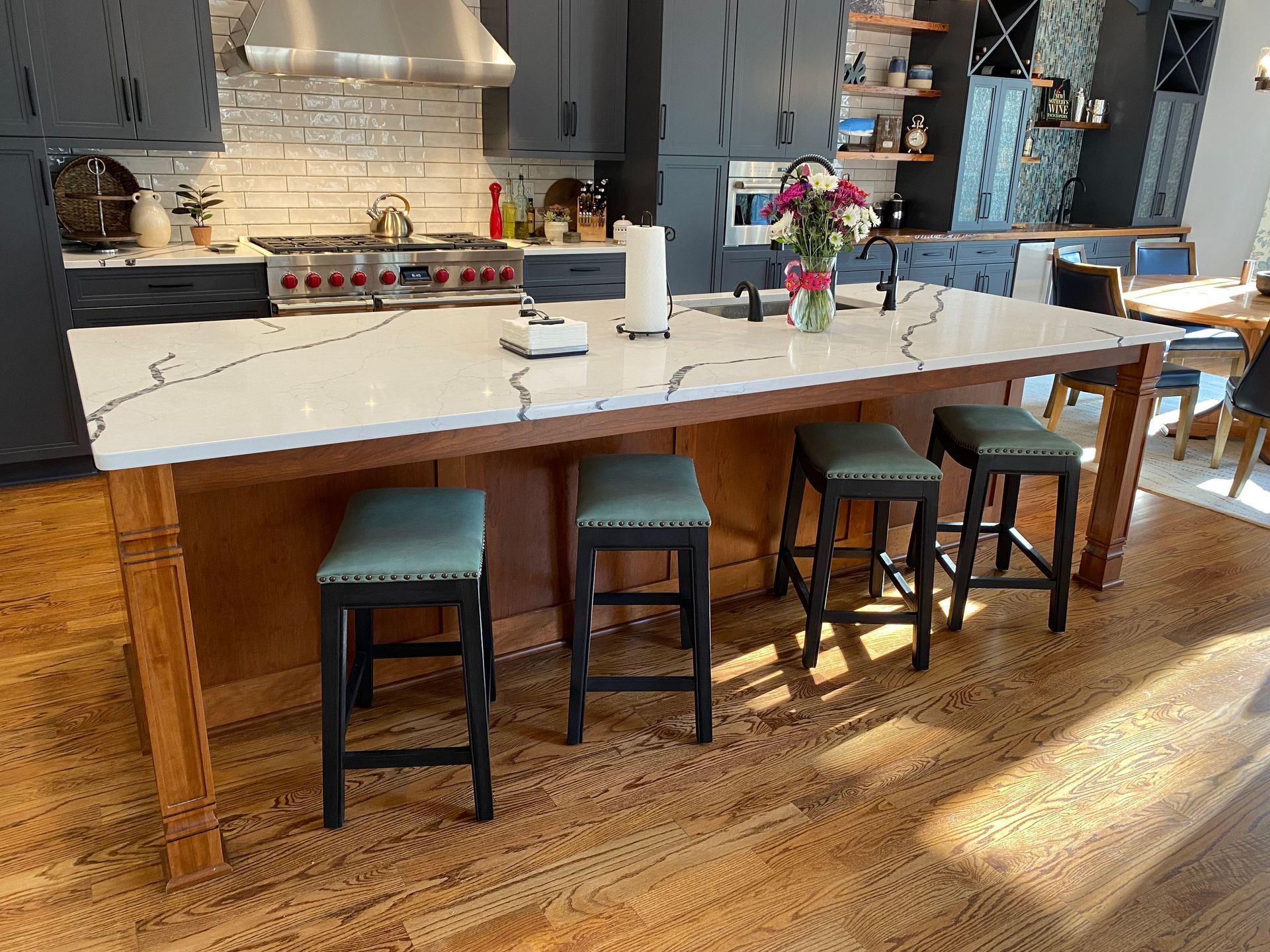 Bar stools at a clear cherry kitchen island with quartz countertop.