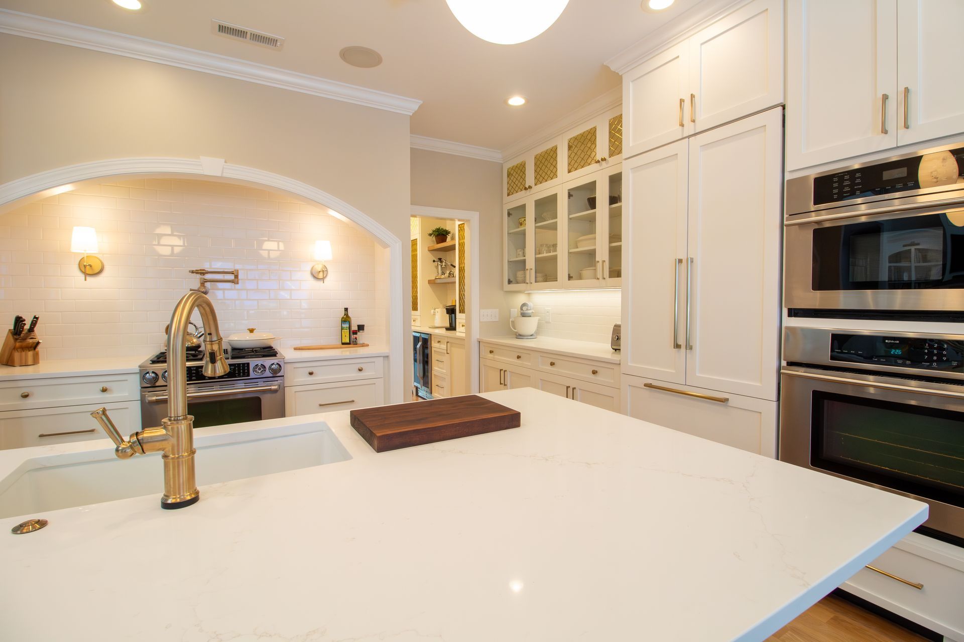 Custom kitchen with a cabinet paneled refrigerator and double wall ovens next to large island.