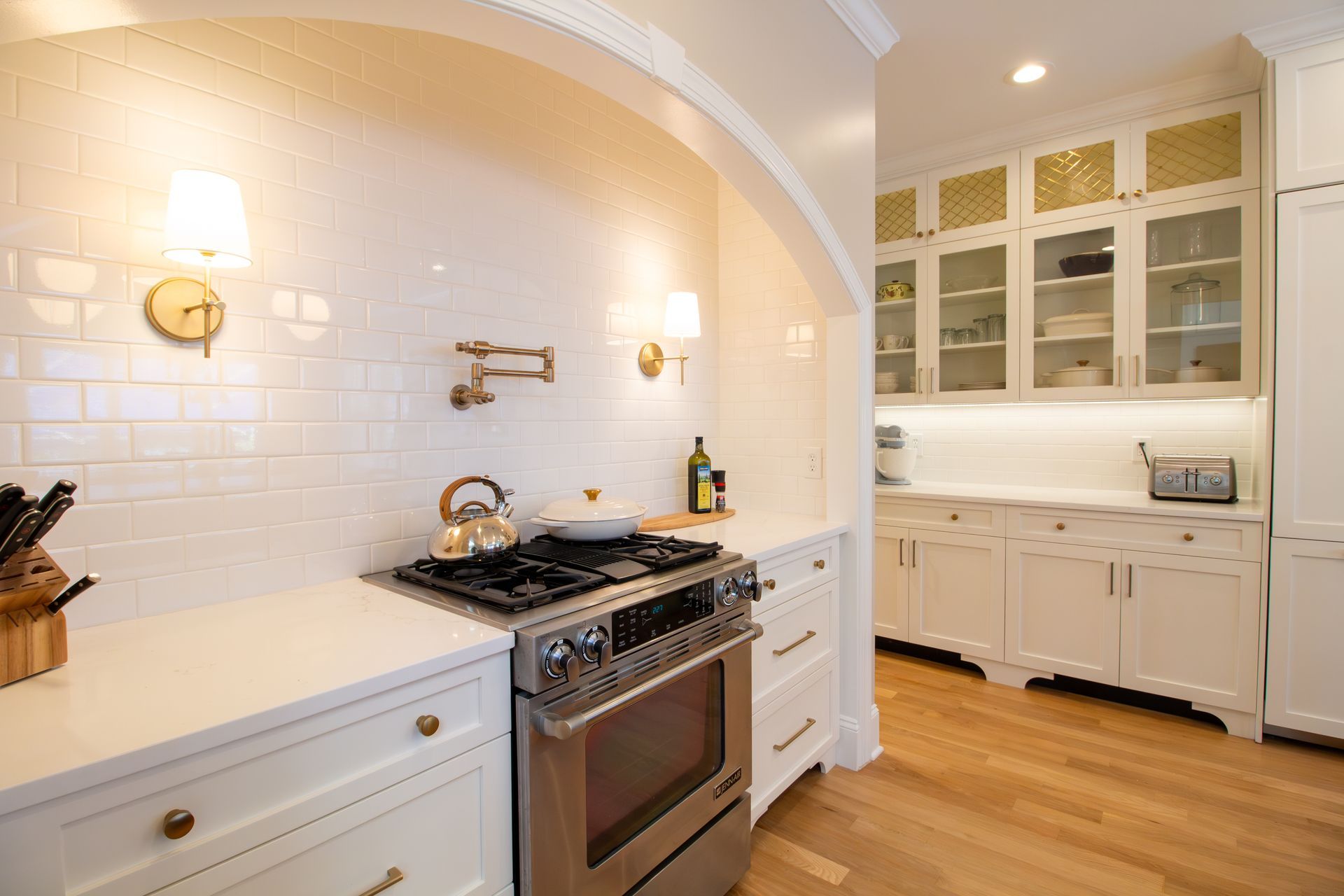 Arched cooking alcove with pot filler and white subway tile backsplash.
