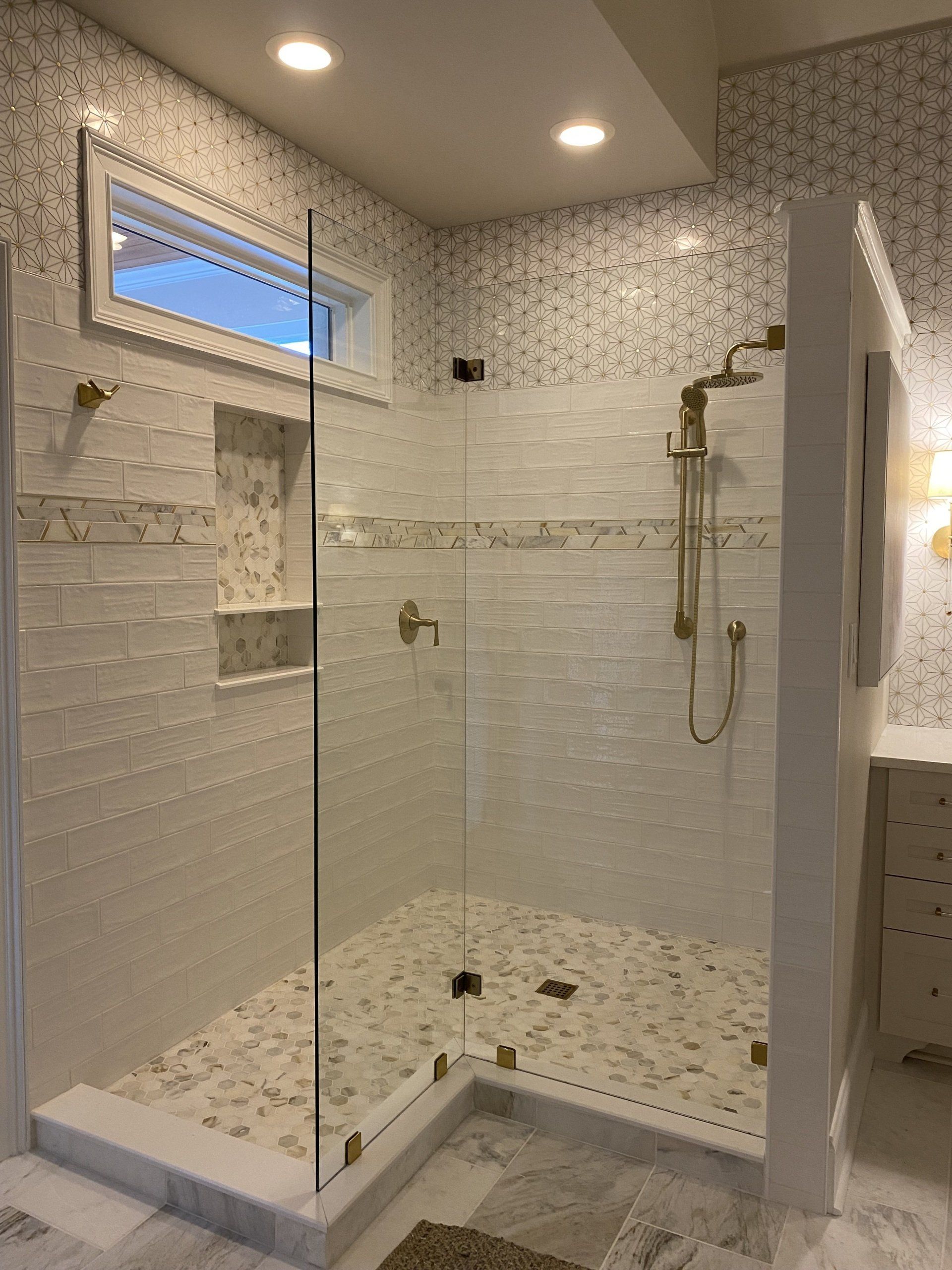 L-shaped walk in tile shower with gold plumbing fixtures.